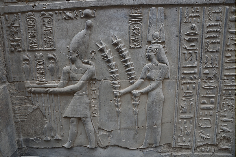 48 MAK_6356.jpg - L'immagine raffigura un faraone (probabilmente Tolomeo VI) insieme a una figura femminile, che potrebbe essere la dea Seshat, che tiene in mano dei lunghi steli di palma. La scena simboleggia la concessione al sovrano di un regno lungo e prospero.